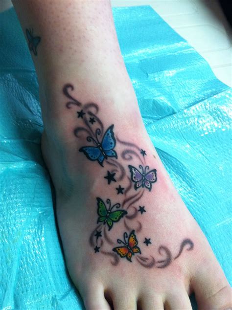 A Butterfly Tattoo On The Foot Of A Person S Foot With Swirls And