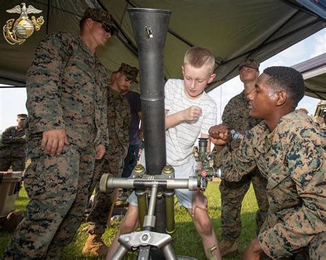 A U S Marine Fist Bumps A Boy Focusing On A M252 81Mm Mortar System Display As Fellow Marines