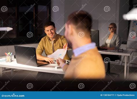 Man Giving Papers To Colleague At Night Office Stock Image Image Of